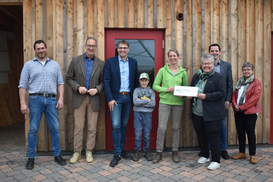 Gruppenfoto mit acht der Personen, die an der Feierlichkeit teilgenommen haben. Gisela Lamkowsky überreicht Claudia Belke das neue Türschuld für das Regionalzentrum.