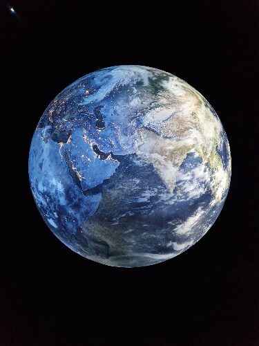 Die Erde aus dem Weltraum betrachtet, ein blauer Planet, zu sehen sind die Lichter der Großstädte