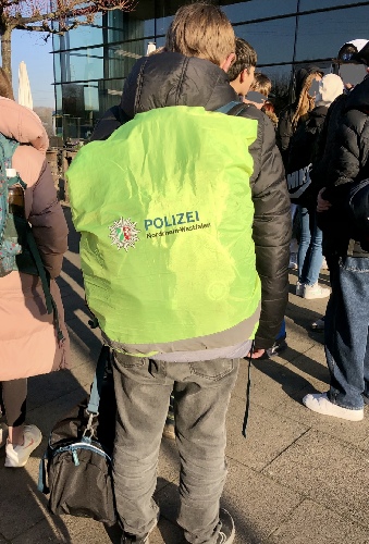 Ein Schüler trägt eine neongelbe Rucksackabdeckung über seinem Schultornister.