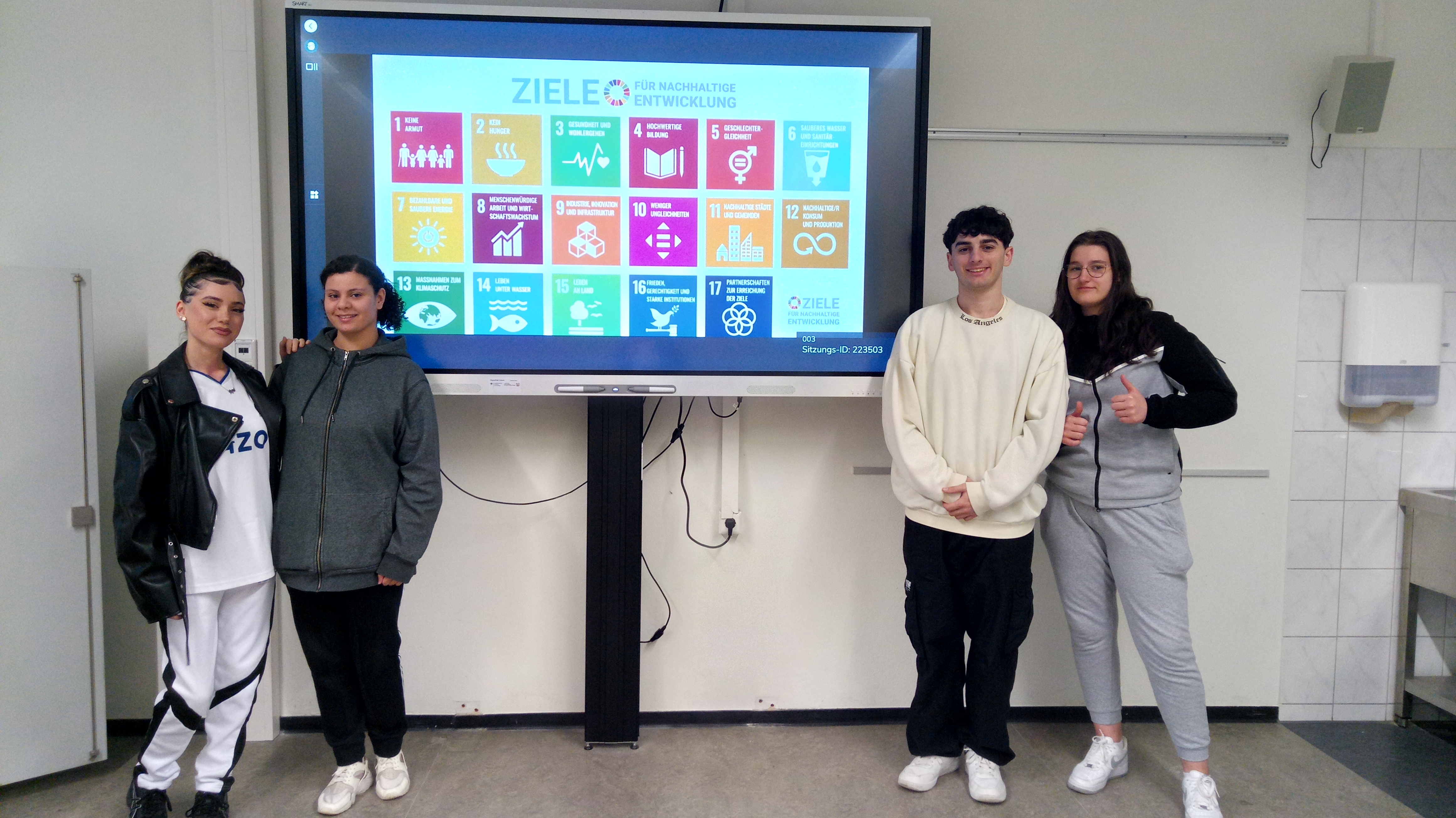 Schüler*innen der Berufsfachschule Servicekräfte vor dem Plakat der  17 SDGs