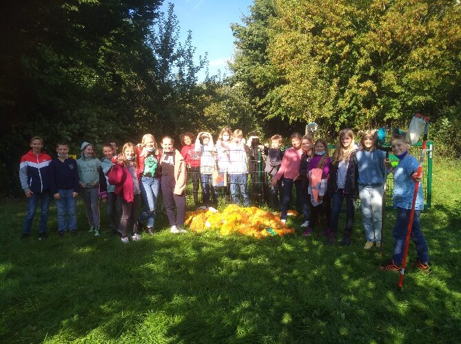 Auf dem Bild sieht man eine SchülerInnengruppe auf der Streuobstwiese als Gruppe posierend und im Vordergrund die geernteten Äpfel. 