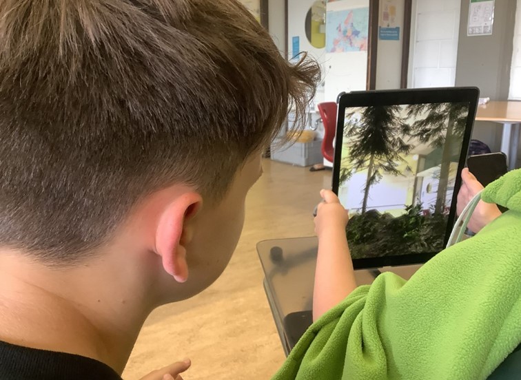 Durch das Ipad erscheint ein Waldbrand im Klassenraum