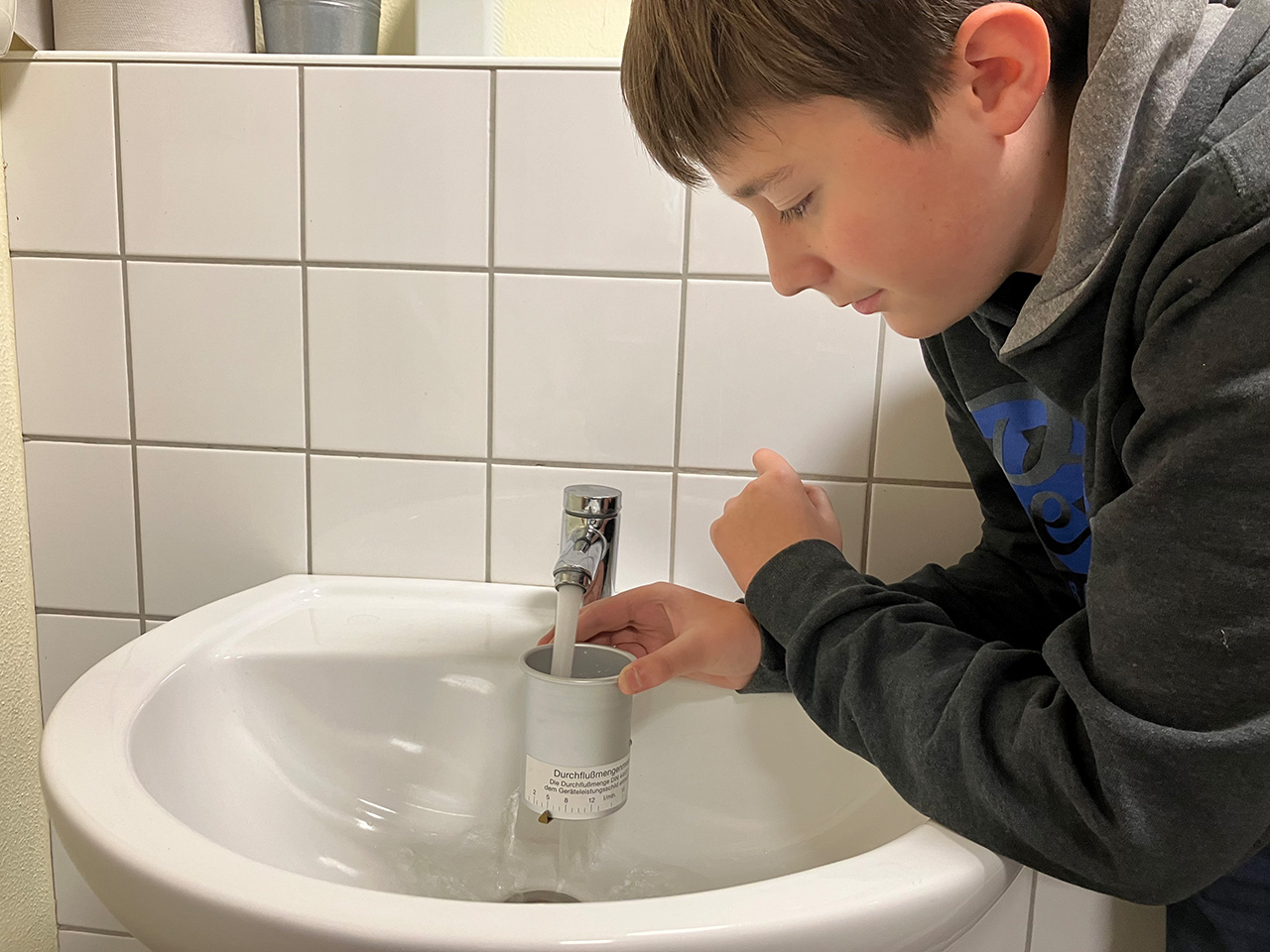 Schüler misst die Durchlaufgeschwindigkeit an den Waschbecken.