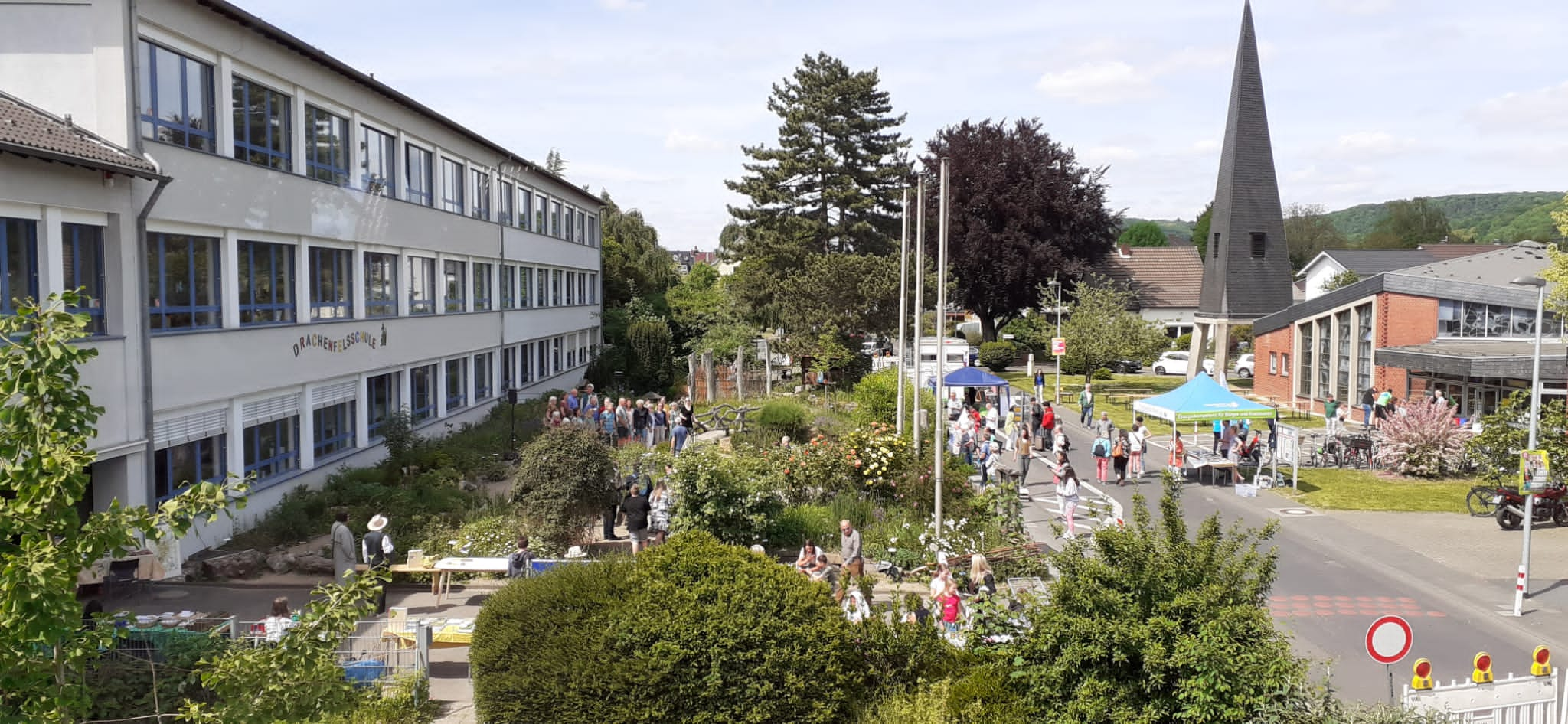 Aus einem höheren Stockwerk fotografiert sieht man den Naturgarten, viele Stände und Menschen