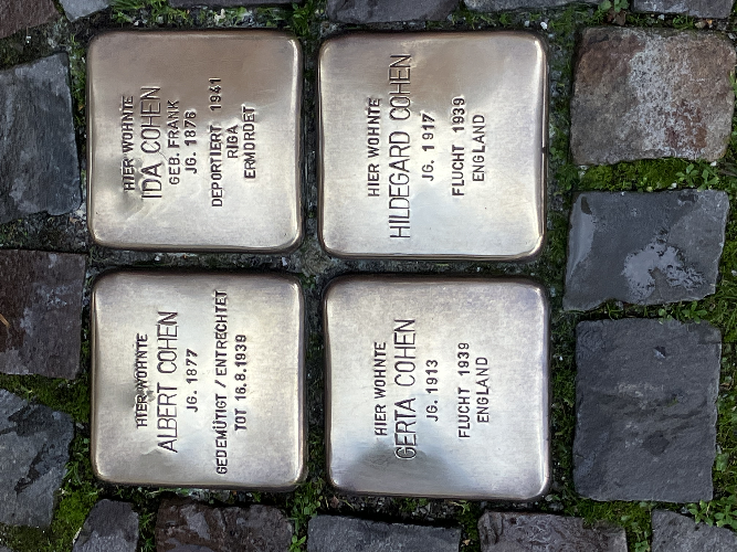 Vier gereinigte Stolpersteine mit der Inschrift ehemaliger jüdischer Coesfelder_innen. Die vier messingfarbenen Steine sind zu einem Quadrat in das Strassenpflaster eingelassen.