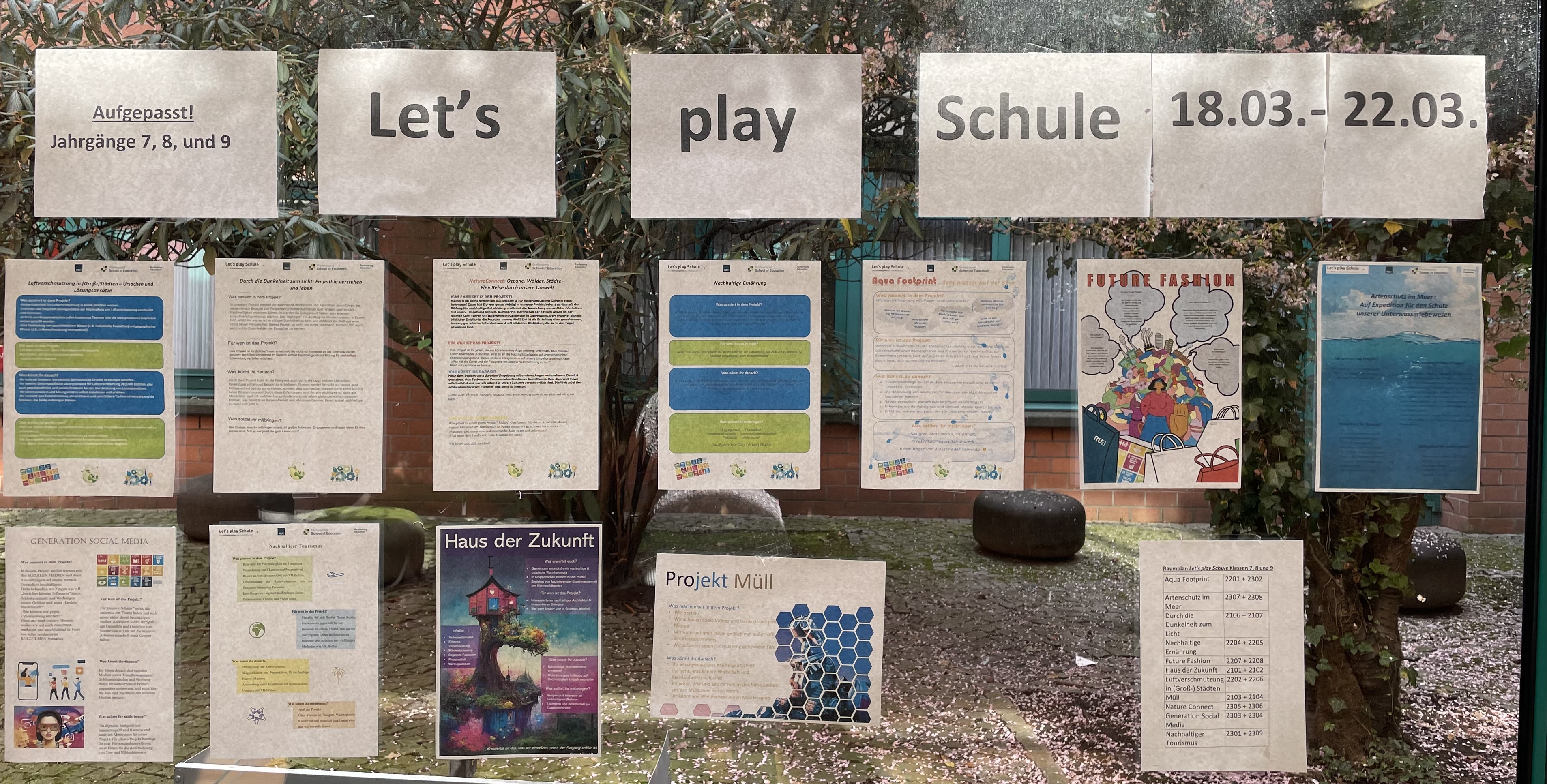 Auf einer Fensterscheibe kleben Infoblätter zu den verschiedenen Projekten von „Let's play Schule