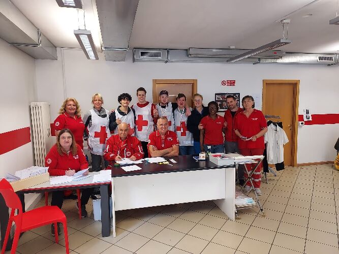 Auf dem Bild ist eine Gruppe von Schüler*innen, Lehrer*innen und Verantwortlichen des Roten Kreuz in Bozen zu sehen. Alle tragen rote Kleidung oder einen weißen Kittel mit einem großen roten Kreuz.
